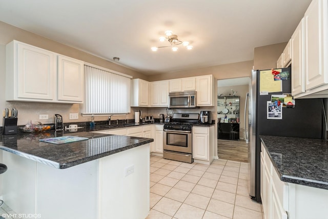 kitchen with kitchen peninsula, appliances with stainless steel finishes, sink, white cabinets, and light tile patterned flooring