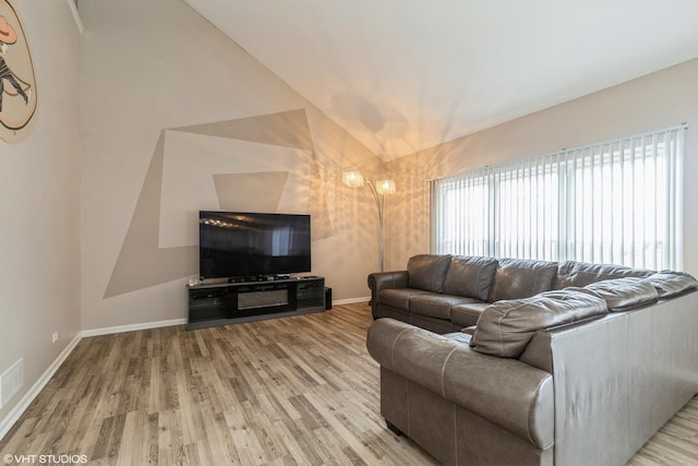 living room featuring light wood-type flooring and vaulted ceiling