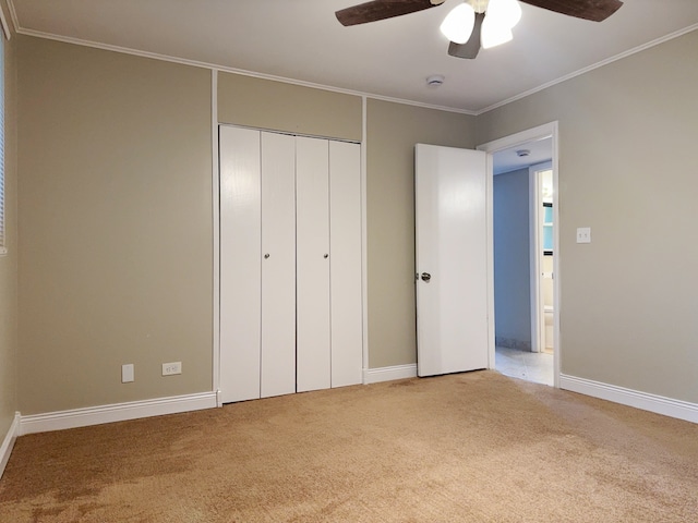 unfurnished bedroom featuring ceiling fan, carpet floors, crown molding, and a closet