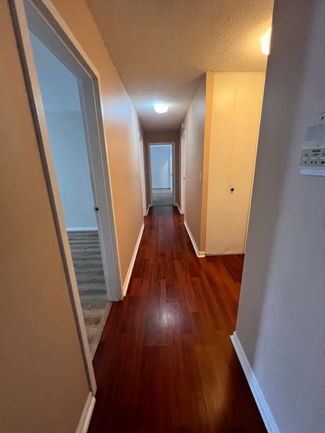 hall with dark wood-type flooring and a textured ceiling