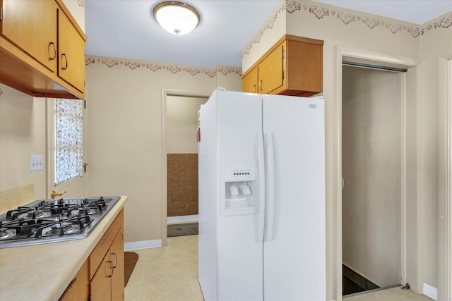 kitchen featuring white fridge with ice dispenser and stainless steel gas stovetop