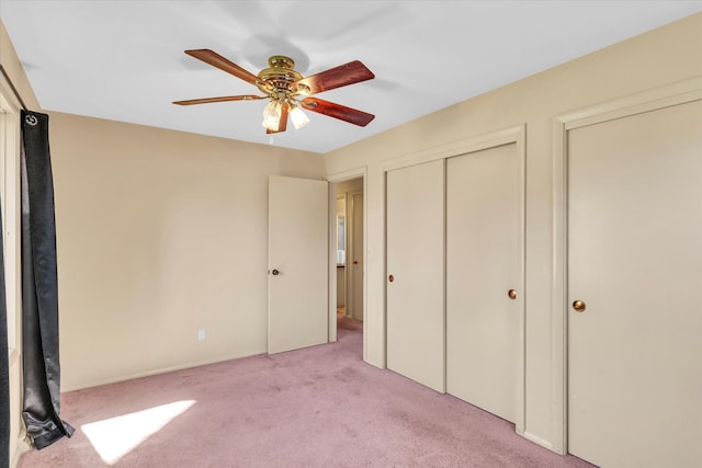 unfurnished bedroom featuring ceiling fan, light carpet, and two closets