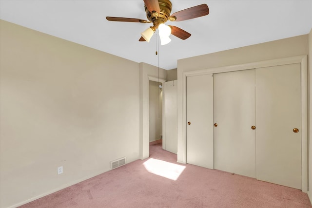 unfurnished bedroom with a closet, light colored carpet, and ceiling fan