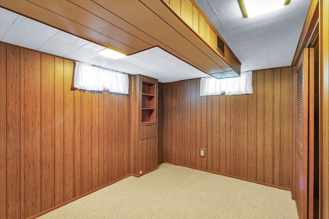 basement with carpet, a healthy amount of sunlight, and wood walls