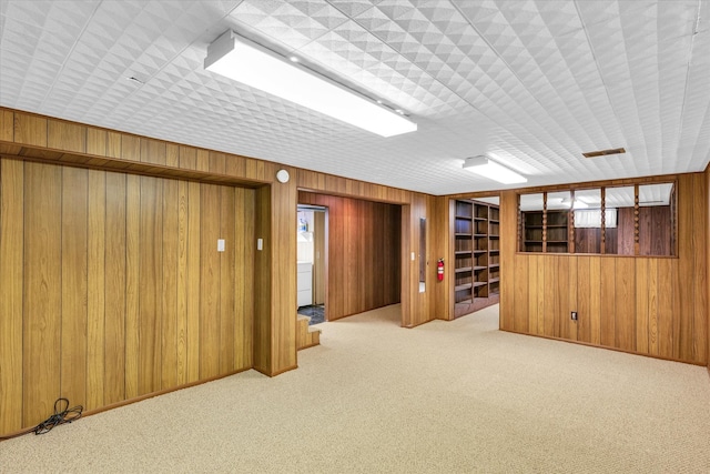 basement featuring wood walls and light colored carpet