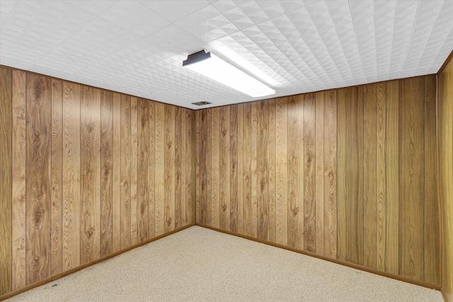 carpeted empty room with wood walls