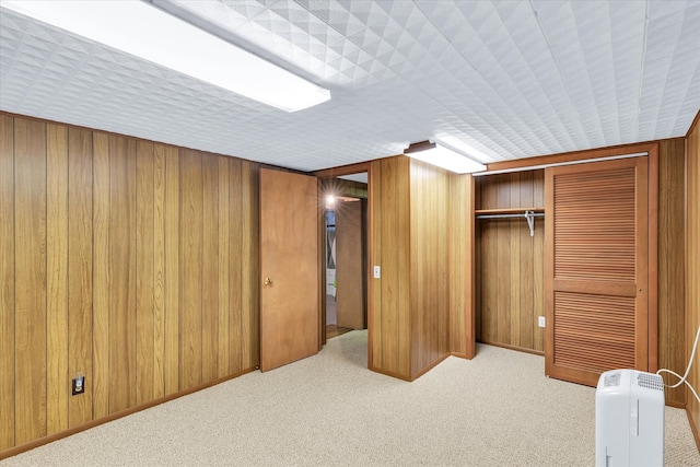 bedroom with wood walls, light colored carpet, and a closet