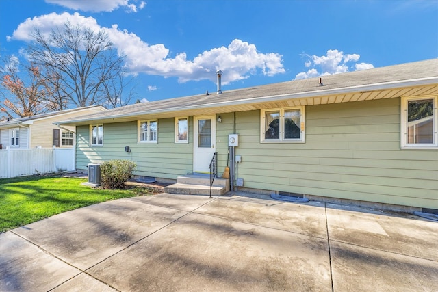 back of property with central AC unit, a patio area, and a lawn