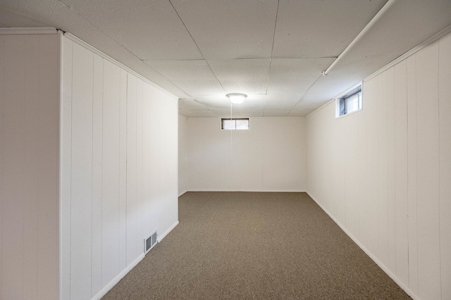 basement featuring carpet and wooden walls