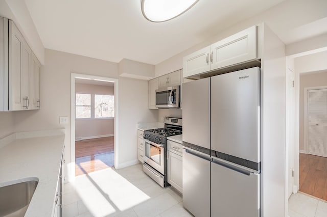 kitchen with sink, white cabinets, light hardwood / wood-style floors, and appliances with stainless steel finishes