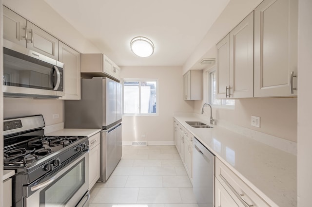 kitchen featuring white cabinets, stainless steel appliances, light tile patterned flooring, and sink