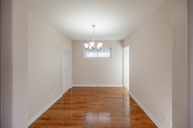 unfurnished dining area featuring a chandelier and light wood-type flooring