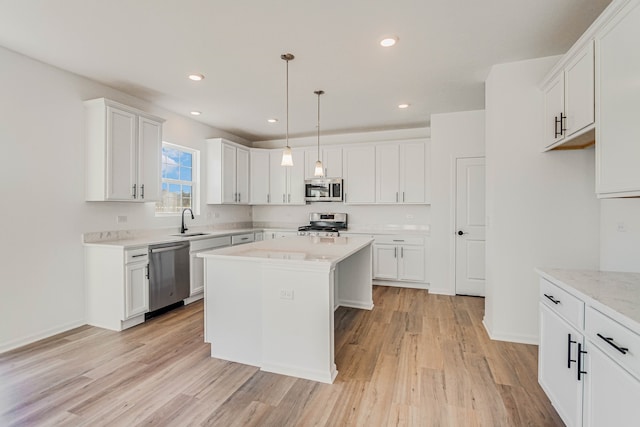 kitchen with sink, hanging light fixtures, light hardwood / wood-style flooring, a kitchen island, and stainless steel appliances