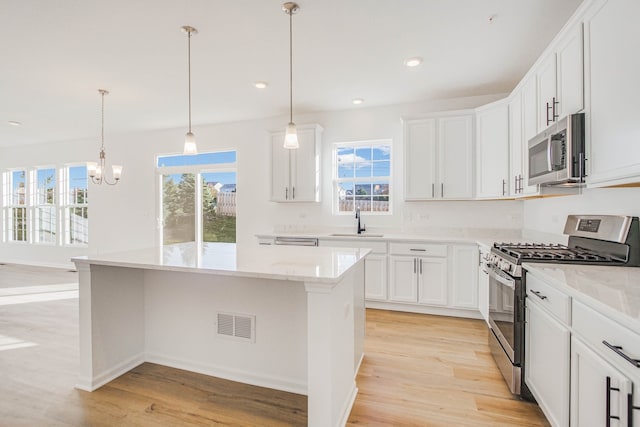 kitchen featuring appliances with stainless steel finishes, light hardwood / wood-style floors, a healthy amount of sunlight, and sink