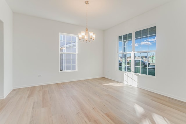 spare room featuring a notable chandelier and light hardwood / wood-style flooring