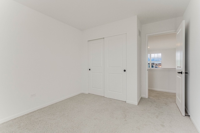 unfurnished bedroom with light colored carpet and a closet