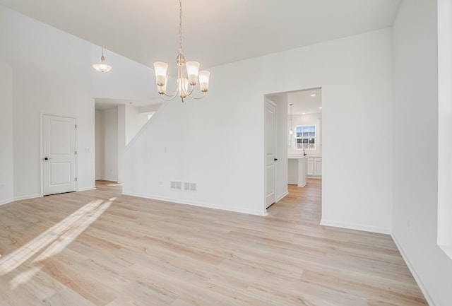 spare room featuring light hardwood / wood-style floors and an inviting chandelier