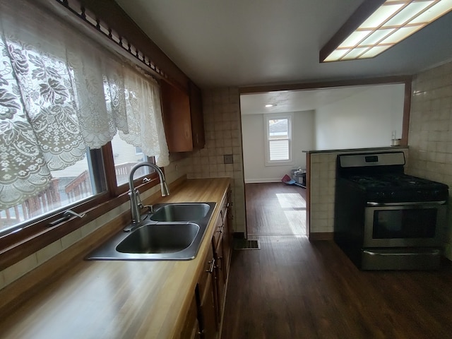 kitchen featuring backsplash, sink, stainless steel range, butcher block countertops, and dark hardwood / wood-style flooring