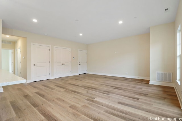 unfurnished bedroom featuring light hardwood / wood-style floors and two closets