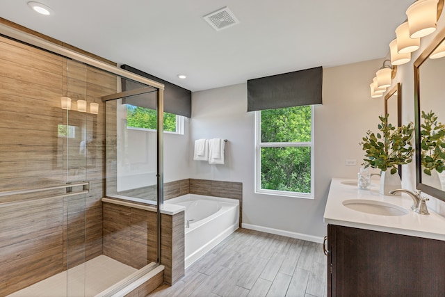 bathroom featuring hardwood / wood-style flooring, vanity, and plus walk in shower