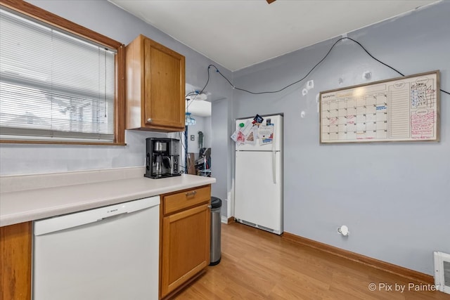 kitchen with white appliances and light hardwood / wood-style flooring