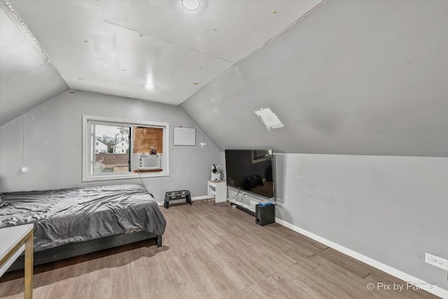 bedroom featuring lofted ceiling, cooling unit, and light wood-type flooring