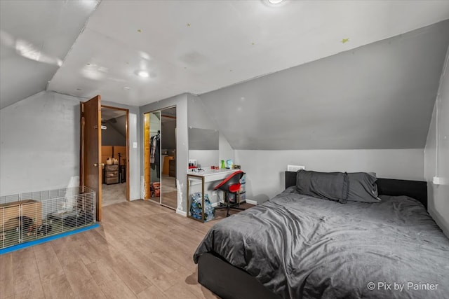 bedroom featuring a closet, light hardwood / wood-style flooring, and vaulted ceiling