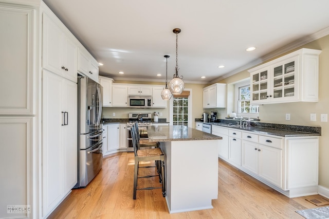 kitchen featuring white cabinets, a center island, dark stone countertops, and stainless steel appliances