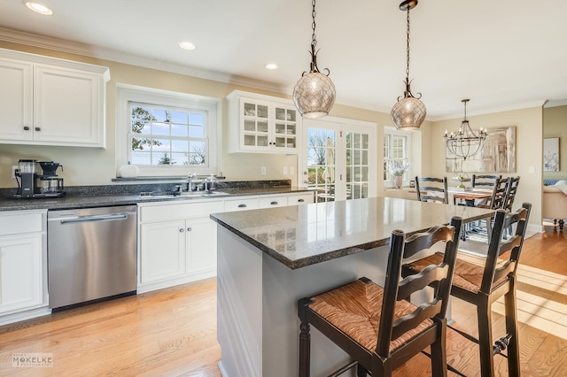 kitchen featuring stainless steel dishwasher, sink, decorative light fixtures, a chandelier, and white cabinetry