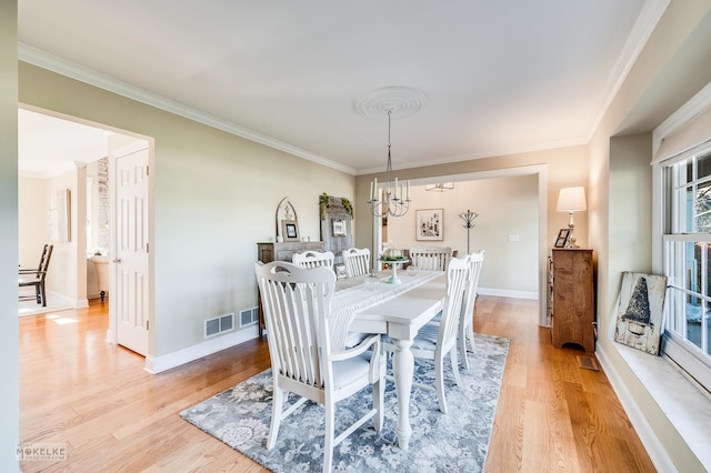 dining room with light hardwood / wood-style flooring, a notable chandelier, and ornamental molding