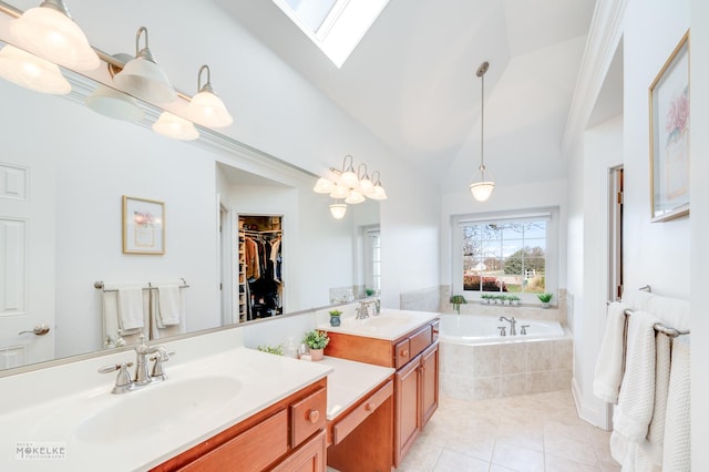 bathroom featuring tile patterned flooring, vanity, a relaxing tiled tub, and vaulted ceiling with skylight