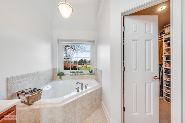 bathroom with tile patterned flooring, vanity, and a relaxing tiled tub