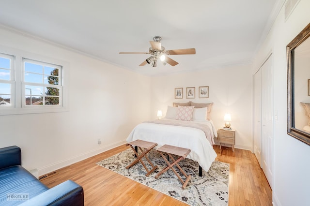 bedroom with ceiling fan, a closet, crown molding, and light hardwood / wood-style flooring