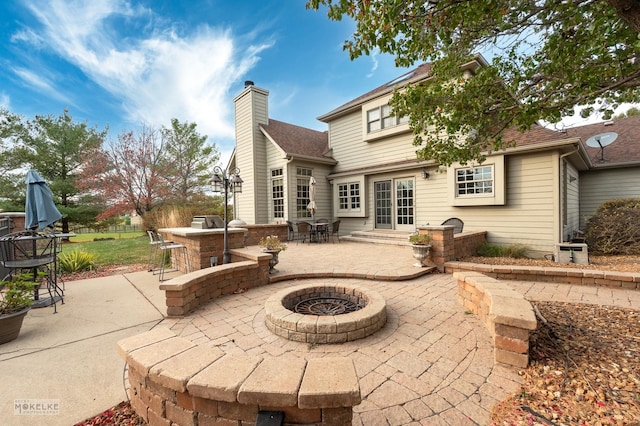 back of property with a fire pit and a patio area