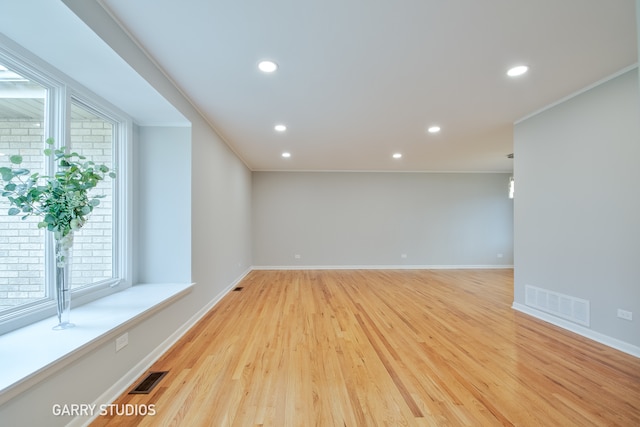 spare room featuring light hardwood / wood-style floors and crown molding