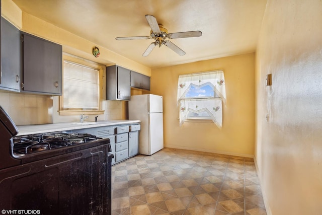 kitchen with black gas range, sink, ceiling fan, gray cabinets, and white fridge