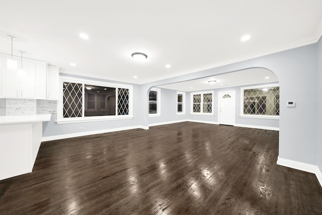 unfurnished living room featuring dark hardwood / wood-style flooring and ornamental molding