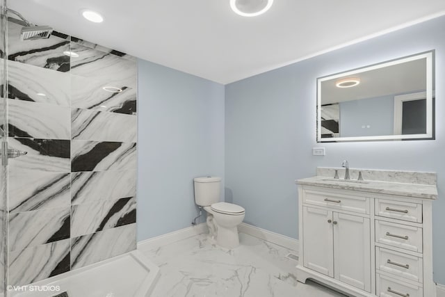 bathroom featuring a tile shower, vanity, and toilet