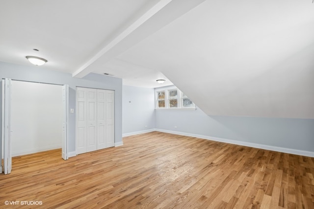 bonus room featuring vaulted ceiling with beams and light wood-type flooring