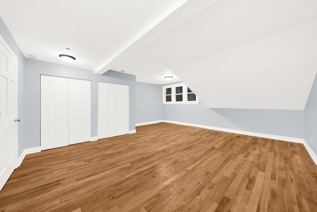 interior space with two closets, hardwood / wood-style flooring, and beam ceiling