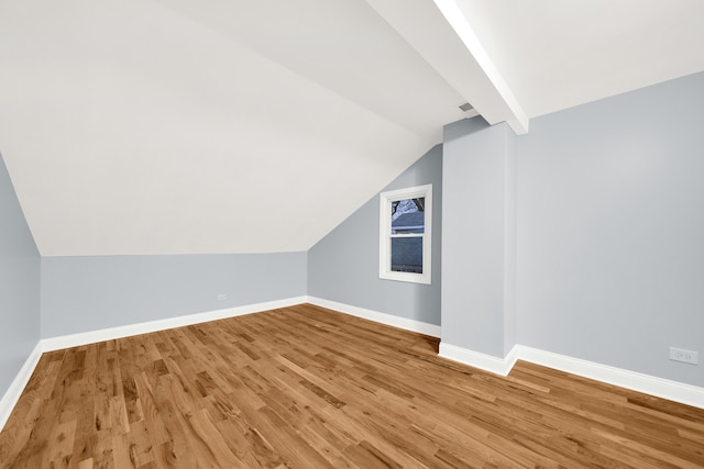 additional living space with hardwood / wood-style floors and lofted ceiling with beams