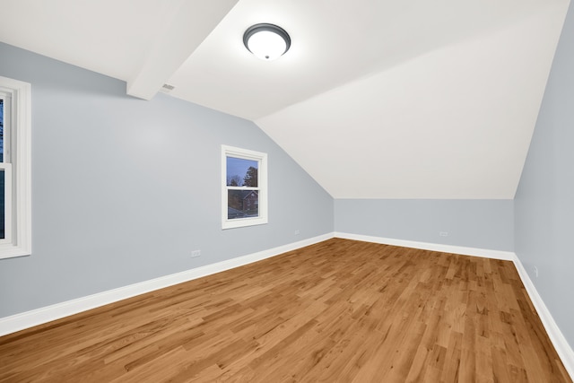 additional living space with lofted ceiling with beams and wood-type flooring