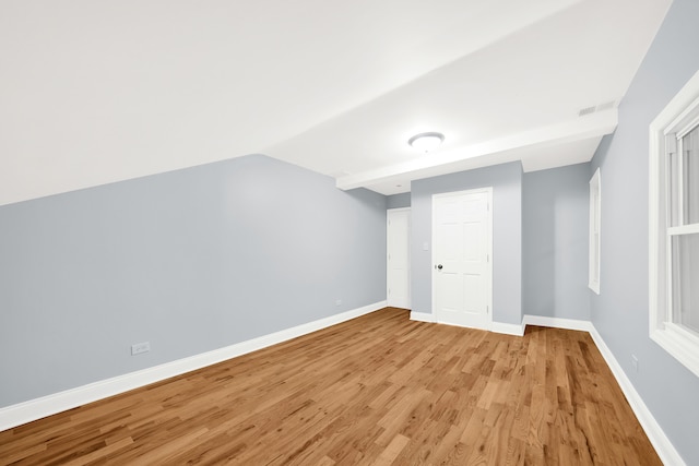 additional living space with vaulted ceiling and light wood-type flooring