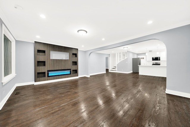 unfurnished living room with a fireplace, crown molding, and dark wood-type flooring