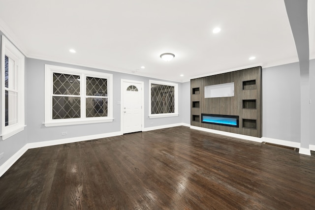 unfurnished living room with a large fireplace, wood-type flooring, and ornamental molding