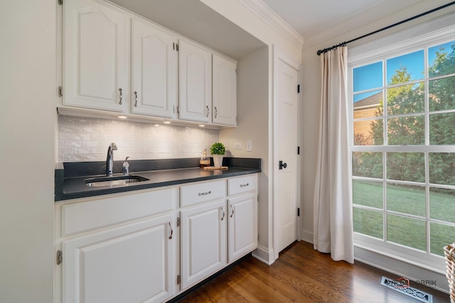 kitchen with white cabinets, sink, decorative backsplash, ornamental molding, and dark hardwood / wood-style flooring