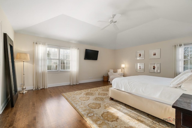 bedroom featuring hardwood / wood-style flooring, ceiling fan, a raised ceiling, and multiple windows