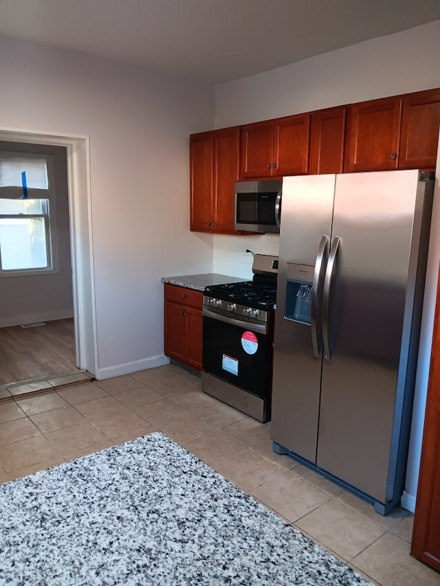 kitchen featuring light tile patterned flooring, light stone counters, and stainless steel appliances