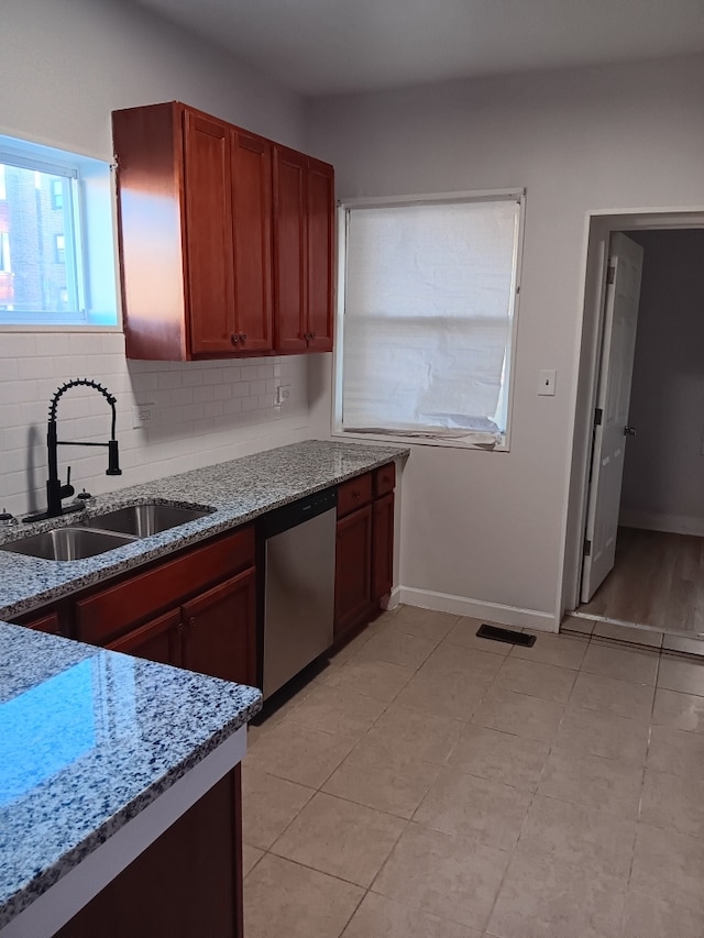 kitchen featuring light stone countertops, decorative backsplash, stainless steel dishwasher, sink, and light tile patterned floors