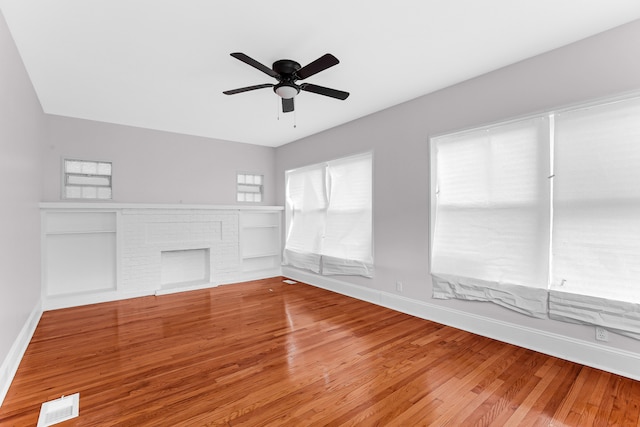 unfurnished room featuring a fireplace, hardwood / wood-style flooring, and ceiling fan